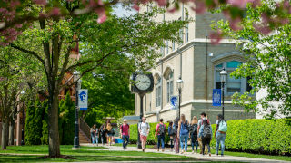 Students walking on campus near the clock tower in Spring.