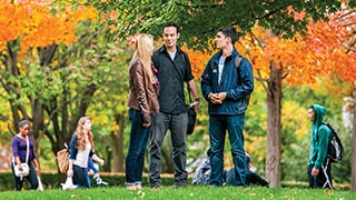 Students talking on the campus Green in the Fall.