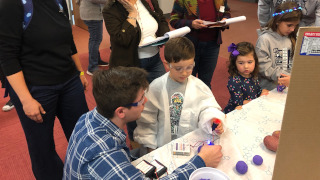 Andrew D’Amato (bottom left) teaching a young chemist whilst the judges look on.