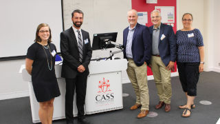 Kathryn Habecker M.P.A. '19, Timothy Hoffman '15/M.P.A. '16, Professor Matthew Hale, Professor Michael Taylor, and Professor Roseanne Mirabella standing together next to a podium