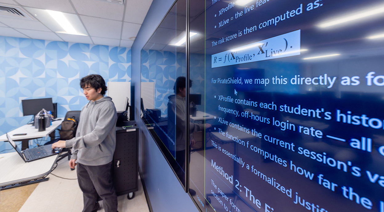 A young man working at a computer workstation in the Cybersecurity lab.