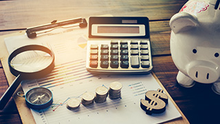 A photo of an invoice, a calculator, a piggy bank and some coins.