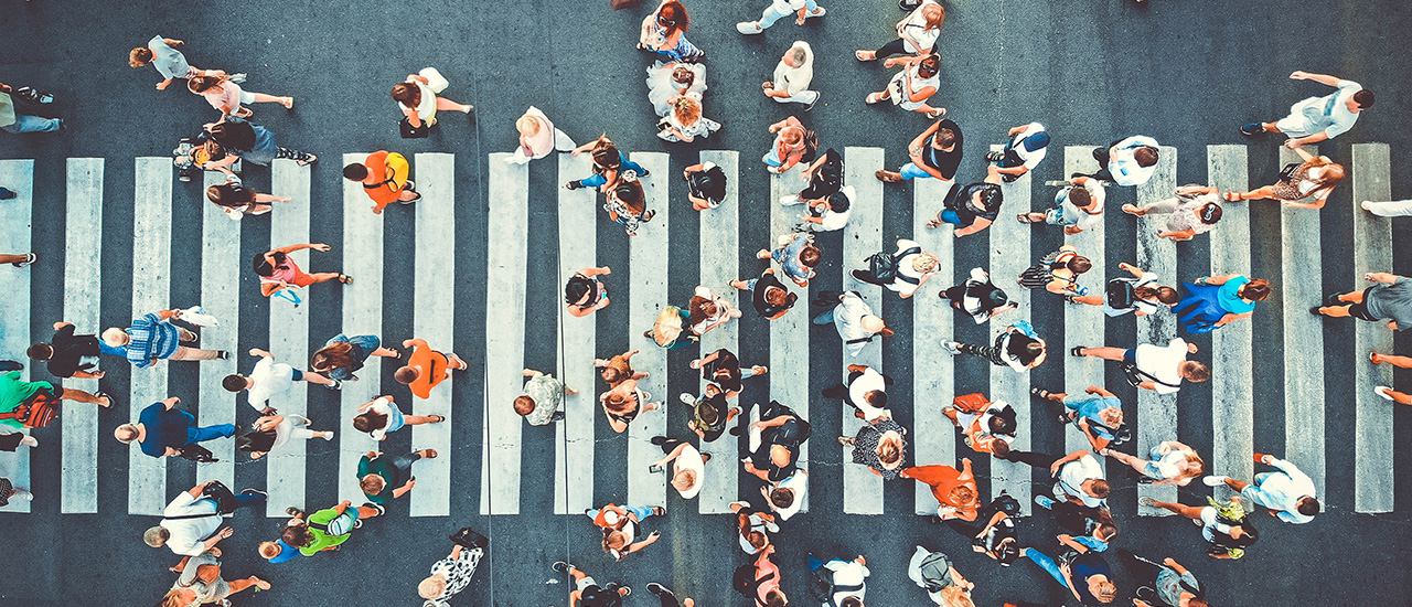 Many people crossing a street at a crosswalk.