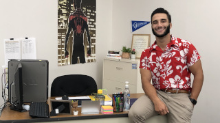 James Lopez sitting on a desk and smiling