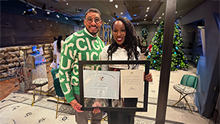  La'Tesha Sampson (right) holds her President’s Lifetime Achievement Award certificate and letter, joined by colleague Juan Rios, associate professor