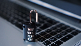 A combination lock on top of a laptop keyboard.