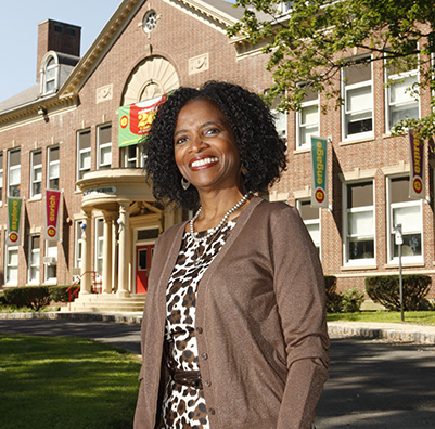 An educator standing in front of a school building.