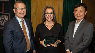 three business professional individuals posing for a photo with an award 