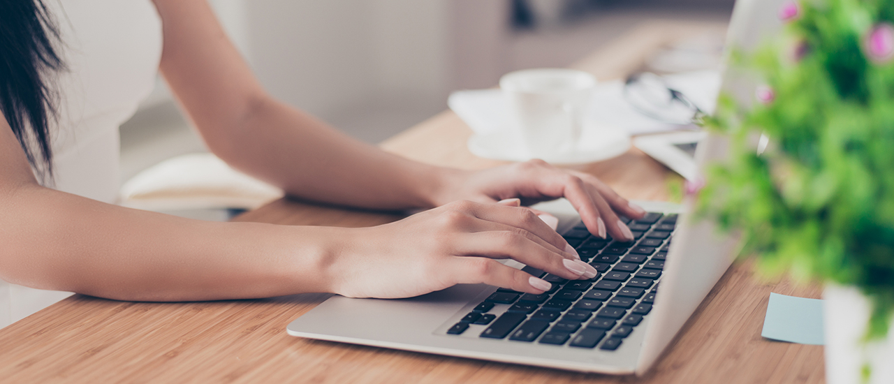 A person typing on a laptop in their home office.