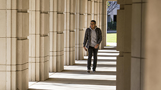 A student walking by the columns in the Walsh Library.