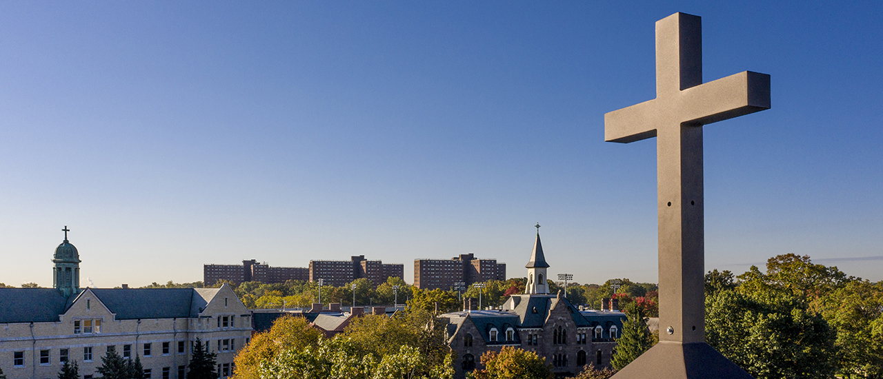 An aerial view of campus with a focus on a Cross on the top of one of the buildings.