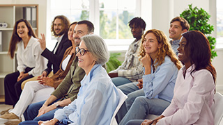 Group of diversity business people sitting in a row on chairs and listening to their colleague.